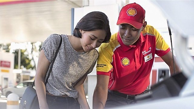 Shell station employee demonstrating to a customer