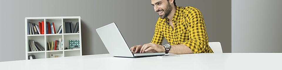 Hombre usando un computador sonriendo frente al computador