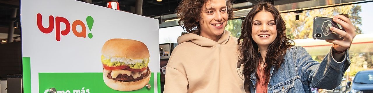 Una pareja de jóvenes se toma una selfie dentro de una tienda de conveniencia upa!