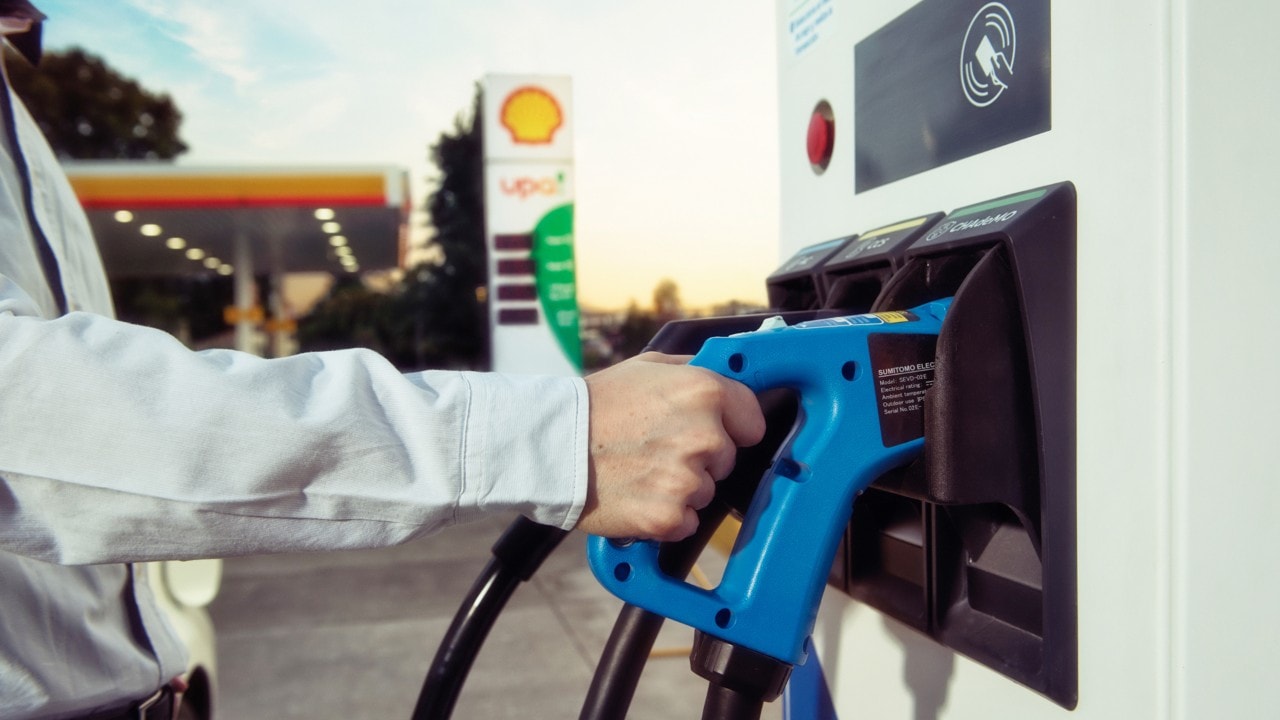 Un cliente tomando por el mango el cargador del tótem de carga E-Pro