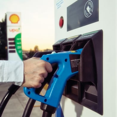 Un cliente tomando por el mango el cargador del tótem de carga E-Pro