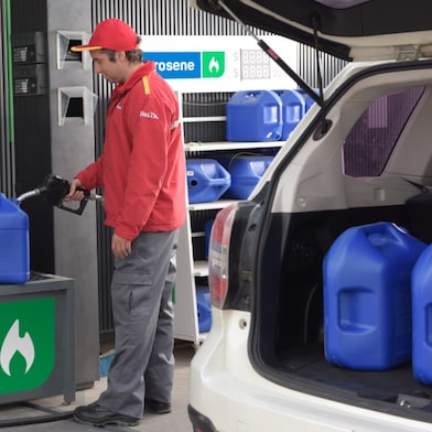 Un atendedor de estación de servicios Shell cargando un bidón con kerosene.