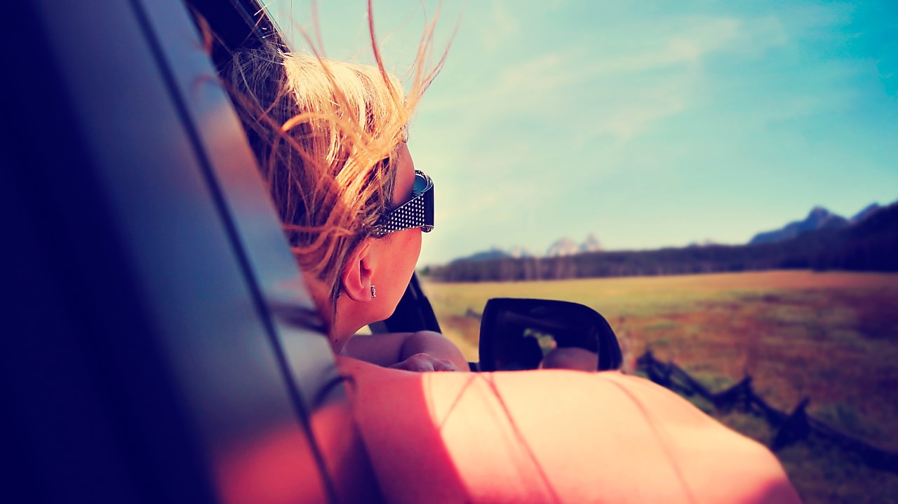 Mujer sacando la cabeza por la ventana del auto